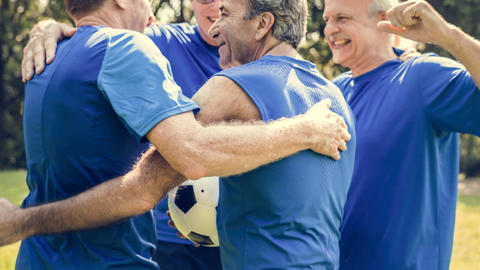 Gruppe älterer Herren, die sich in Sportkleidung umarmen