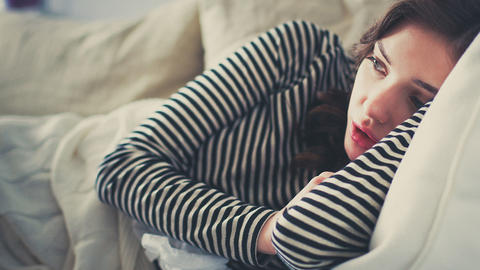 Frau liegt erschöpft auf Sofa