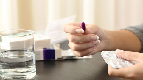 Frau nimmt Medikamente mit Wasser ein