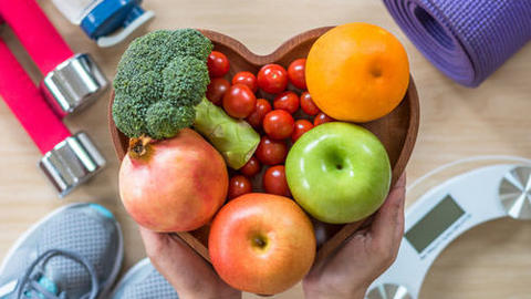 Abbildung von Sportschuhen, Waage, Hanteln und Obst und Gemüse.