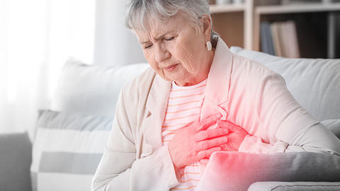 Frau fasst sich mit Schmerzen an die Brust