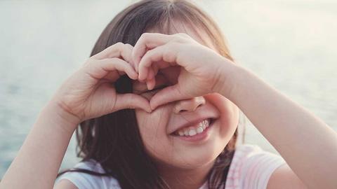 Kind, dass mit Ihren Händen ein Herz formt