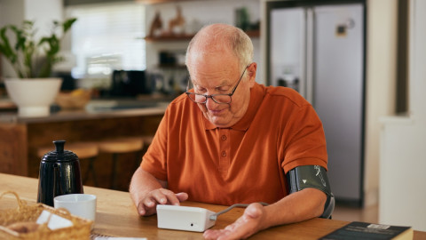 Senior misst am Küchentisch den Blutdruck