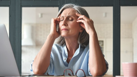 Frau telefoniert und fasst sich dabei an die Stirn